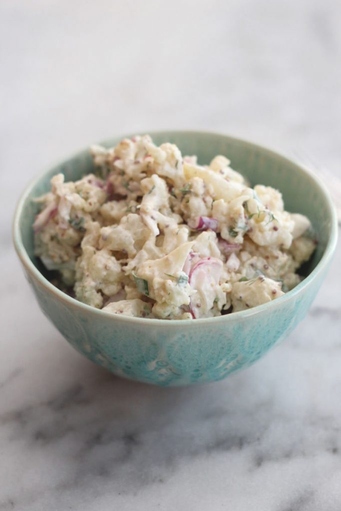 Cauliflower "potato" salad with radishes in a green bowl.