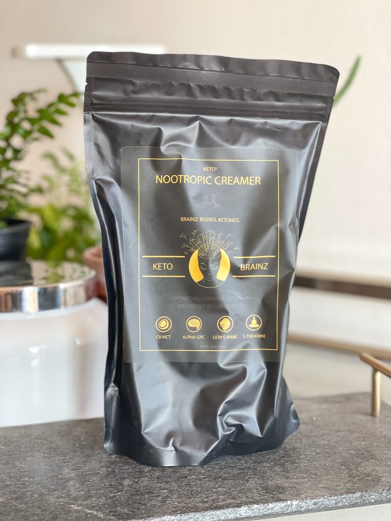 Image of a bag of Keto Brainz nootropic creamer with plants in the background.