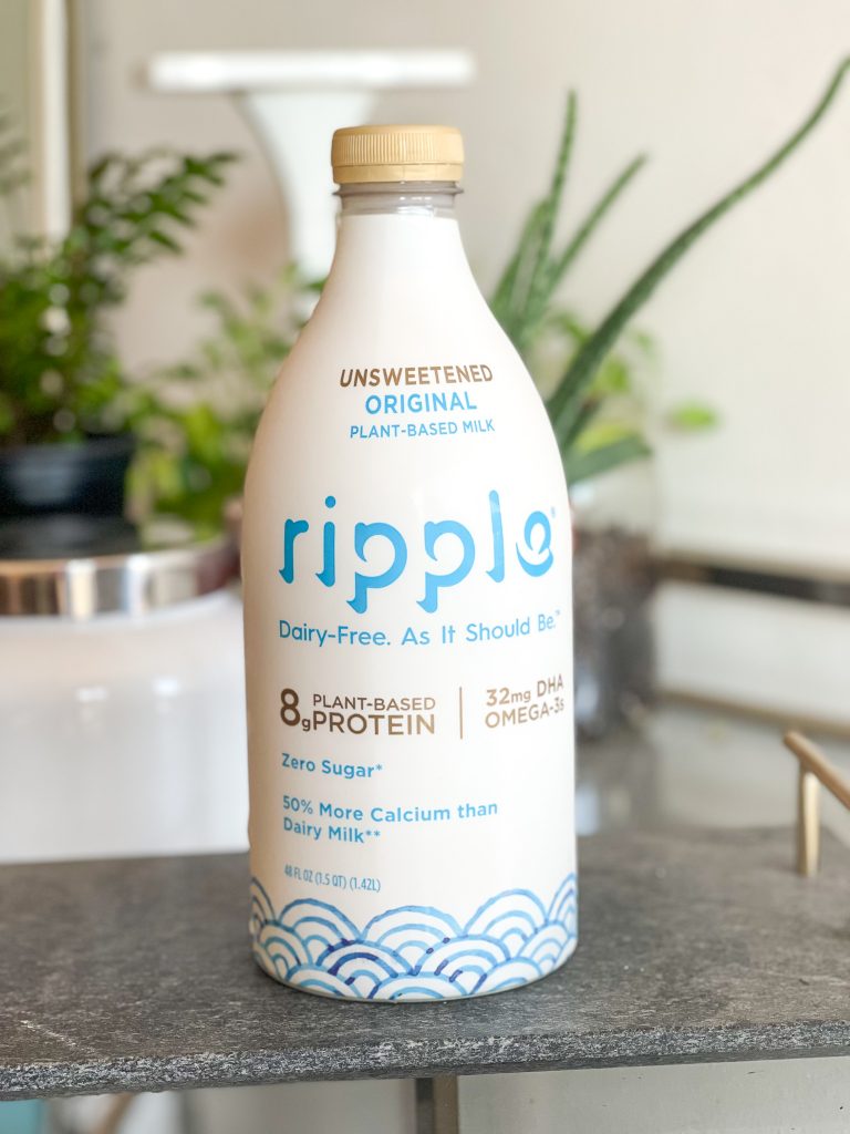 Image of Ripple dairy free milk container with plants in the background.